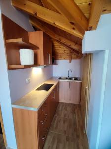 a small kitchen with wooden cabinets and a sink at Lovely 1 - bedroom loft with free parking in Gjirokastër
