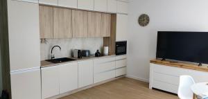 a kitchen with white cabinets and a flat screen tv at Mazurski relax plus Taras Garaż podziemny in Węgorzewo