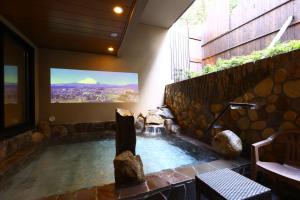a hot tub in a room with a tv on the wall at Dormy Inn Express Fujisan Gotemba in Gotemba