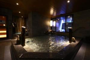 a bathroom with a large tub with rocks in it at Dormy Inn Express Fujisan Gotemba in Gotemba