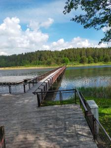 a wooden bridge over a lake with trees in the background at 2-ju kambariu butas in Ignalina