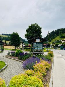 a sign in the middle of a garden with flowers at Moserwirt Pension in Sankt Veit an der Glan