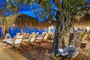 a group of chairs and a tree on a deck at By the sea luxury suites in Limenas