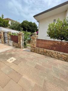 a house with a brick fence and a stone wall at Trilo Lu Rattali in San Teodoro