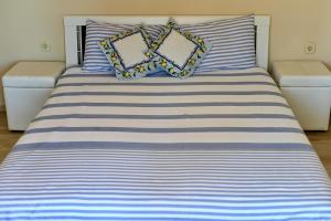 een bed met blauwe en witte gestreepte lakens en kussens bij Апартамент Limoncini in Sozopol