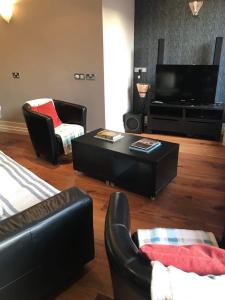 sala de estar con muebles negros y TV de pantalla plana en Centre of Dingle Town - Luxury Holiday Apartment en Dingle