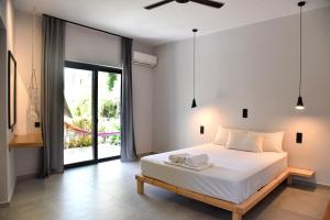 a bedroom with a white bed and a large window at Galini Studios & Apartments-Adults only in Sougia