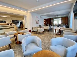 un hall avec des chaises et des tables blanches ainsi qu'un piano dans l'établissement Hotel Sciatori, à Temù