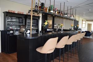 a bar with a row of white stools at Fletcher Duinhotel Hotel Burgh Haamstede in Burgh Haamstede