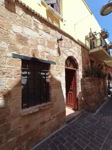 a stone building with a red door and a brick street at Katerina Traditional Rooms in Chania