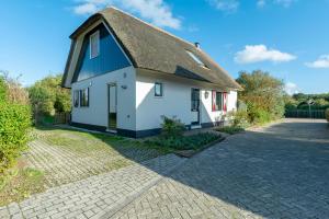een wit en blauw huis met een rieten dak bij Buitenplaats 89 Callantsoog in Callantsoog