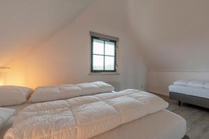 een witte kamer met 2 bedden en een raam bij Buitenplaats 89 Callantsoog in Callantsoog