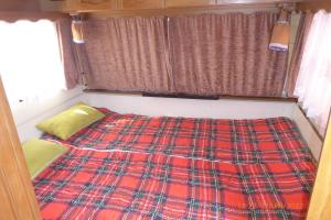 Bett in einem kleinen Zimmer mit einer karierten Decke in der Unterkunft Bungalow nebst Wohnwagen für 4 bis 5 Personen in Nähe von See- und Tesla 