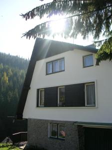 a white house with black shutters on it at Ubytování U Vořechovských in Pec pod Sněžkou