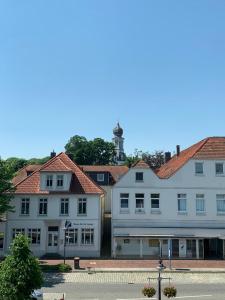 een groep gebouwen met een vuurtoren op de achtergrond bij Schloss Blick Bredendiek OG in Jever