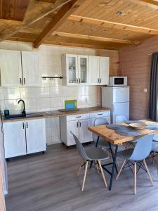 a kitchen with white cabinets and a table and chairs at Domki Balos in Karwia