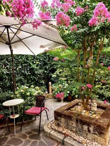 un giardino con tavolo, sedie e fiori rosa di Hotel Arcoveggio a Bologna