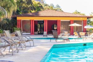 a resort with a swimming pool with chairs and umbrellas at Hotel Caminhos de Itaipava in Itaipava
