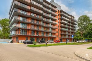 apartamentowiec z samochodami zaparkowanymi przed nim w obiekcie Jantar Apartamenty- Wyspa Solna w Kołobrzegu