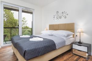 biała sypialnia z dużym łóżkiem i oknami w obiekcie Jantar Apartamenty- Wyspa Solna w Kołobrzegu