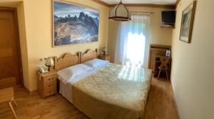um quarto com uma cama e um quadro na parede em Albergo Garnì Ajarnola em Auronzo di Cadore