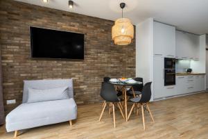 a living room with a table and chairs and a tv on a brick wall at Czarna Perła- Apartament przy Solisku in Szczyrk