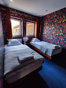 two beds in a room with floral wallpaper at Nata Pokoje Gościnne Restauracja in Libiąż