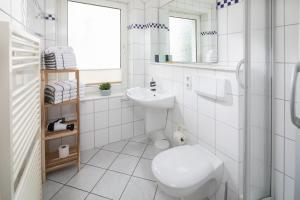 a white bathroom with a toilet and a sink at Lüttje Schmiede in Norderney