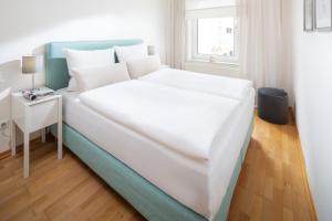 ein großes weißes Bett in einem Zimmer mit einem Tisch in der Unterkunft Lüttje Schmiede in Norderney