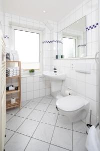 Baño blanco con aseo y lavamanos en Lüttje Schmiede en Norderney