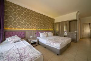 a bedroom with two beds and a wall with purple wallpaper at Lykia Botanika Beach Fun & Club - All Inclusive in Fethiye
