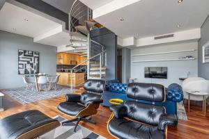 a living room with leather furniture and a spiral staircase at Penthouse Suite at Cartwrights Corner in Cape Town