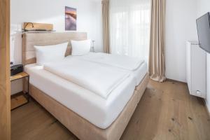 een groot wit bed in een kamer met een televisie bij Friesenhuus Friesenhuus Norderney, Whg 02 in Norderney