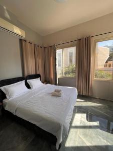 a bedroom with a large white bed and two windows at Diamond Studio Apartment - Haifa in Haifa