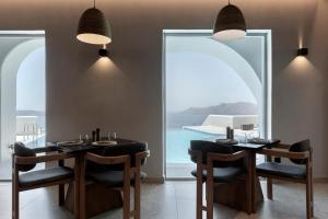 Hom Santorini في أويا: غرفة طعام مع طاولتين وإطلالة على المحيط