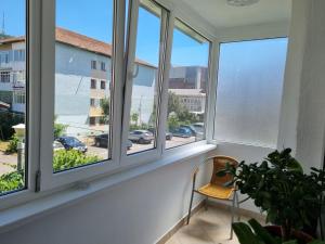 een kamer met ramen met een stoel en uitzicht op een straat bij D&Y Apartments in Piatra Neamţ