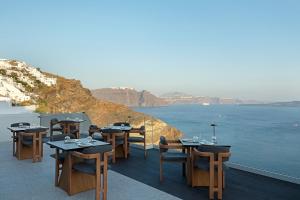 Hom Santorini في أويا: مطعم بطاولات وكراسي يطل على الماء