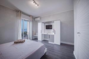 B&B "La Vista Preziosa" Feeling Home في غالّيبولي: غرفة نوم بيضاء فيها سرير وتلفزيون