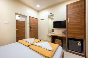een slaapkamer met een bed, een bureau en een televisie bij Hotel Balwas in Mumbai