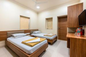 2 aparte bedden in een kamer met een televisie bij Hotel Balwas in Mumbai