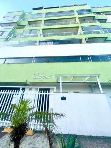 un grande edificio verde con un cancello bianco e palme di Eu Amo Arraial Hospedagem - Prainha 3 Quartos com Ar condicionado ad Arraial do Cabo