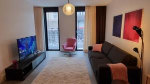 a living room with a couch and a pink chair at Uusi, avara, saunallinen keskustakaksio in Tampere