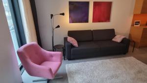 a living room with a couch and a pink chair at Uusi, avara, saunallinen keskustakaksio in Tampere