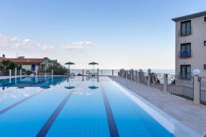 a swimming pool next to a building and the ocean at Hotel Brancamaria in Cala Gonone