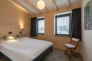 een slaapkamer met een bed en 2 ramen bij Previnaireweg 5 Callantsoog in Callantsoog