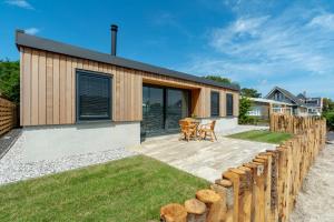 een modern huis met een houten hek en gras bij Previnaireweg 5 Callantsoog in Callantsoog