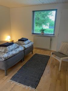 - 2 lits dans une chambre avec une fenêtre et un tapis dans l'établissement Feriehus-Gammel Byvej, Vrensted, à Løkken