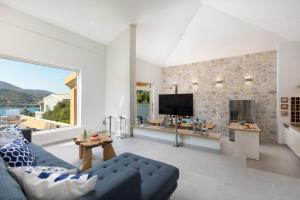 Una sala de estar con un sofá azul y una pared de piedra. en Villa Apanemia by Villa Plus, en Kassiopi
