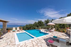 a swimming pool with chairs and an umbrella at Villa Maria Kassiopi by Villa Plus in Kelliá