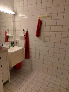 Baño de azulejos blancos con lavabo y toallas rojas en Shared apartment, Down Town Oslo, Osterhaus'gate 10, en Oslo